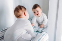 Bébé garçon ludique regardant miroir et faire des visages — Photo de stock