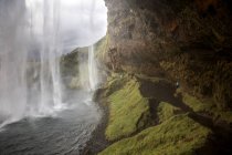Éclaboussures de cascade de falaises rocheuses vertes, Islande — Photo de stock