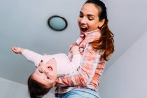 Mutter spielt mit Baby vor weißer Wand — Stockfoto