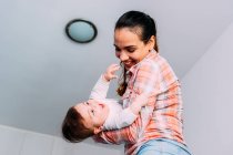 Mother playing with baby boy in front of white wall — Stock Photo