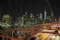 Vehicles riding on modern bridge over river in New York city at night, USA — Stock Photo