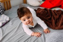 Retrato de bebé curioso agachado en la cama - foto de stock