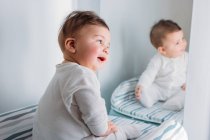 Amazed sweet baby boy looking at mirror in nursery — Stock Photo