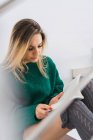 Frau in grünem Pullover und Strümpfen sitzt und liest Buch — Stockfoto