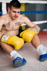 Shirtless boxer confiante em luvas sentado nas fezes no ringue. — Fotografia de Stock
