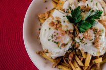 Аппетитная порция яиц, подаваемых в тарелке с картошкой фри — стоковое фото