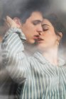Чувственный молодой человек и женщина целуются за окном — стоковое фото