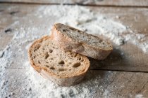 Scheiben frisches, appetitanregendes Brot in Mehl auf grobem Holztisch — Stockfoto