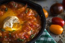 Жареное яйцо с помидорами, красным перцем и хлебом в сковороде — стоковое фото