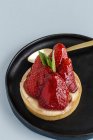Deliciosa sobremesa preenchida com creme e morangos frescos no prato no fundo azul — Fotografia de Stock