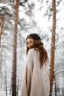 Young pretty woman standing in winter forest and looking back at camera. — Stock Photo