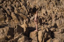 Side view of unrecognizable attractive nude woman standing on rock in sunny day. — Stock Photo