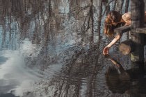 Голая женщина лежит и трогает воду — стоковое фото