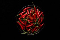 Pan of red hot peppers on black background — Stock Photo