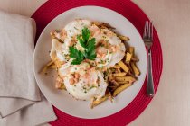 Аппетитная порция яиц, подаваемых в тарелке с картошкой фри — стоковое фото