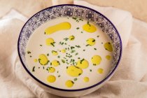Close-up of cream soup with oil in patterned bowl on white cloth — Stock Photo