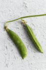 Close-up of green peas on white shabby surface — Stock Photo