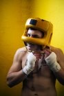 Hombre boxeador sin camisa que se pone el casco para la lucha. - foto de stock