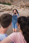 Женщина фотографирует детей на смартфоне на пляже — стоковое фото