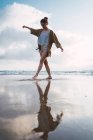 Junge Frau läuft im Wasser am Sandstrand — Stockfoto