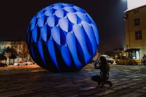 Grande monumento a sfera blu illuminato di notte e fotografo prendere spettacoli. — Foto stock