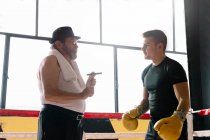 Вид сбоку взрослого мужчины с боксером для тренировки сигар в тренажерном зале. — стоковое фото