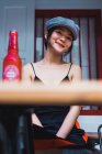 Elegante jovem mulher asiática sentada no café e tendo garrafa de bebida. — Fotografia de Stock