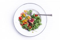 Зверху тарілка випробувального овочевого салату з інжиром, подається з виделкою . — стокове фото