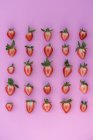 View from above of halves of strawberries on pink background — Stock Photo