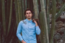 Nachdenklicher junger gutaussehender Mann bei Kaktus — Stockfoto