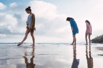 Woman and teenage girls walking together on beach — Stock Photo