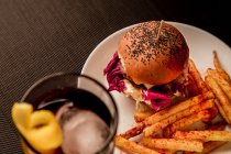 Hambúrguer saboroso com batatas fritas em prato e copo de coca — Fotografia de Stock