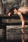 Donna nuda sdraiata e toccante acqua — Foto stock