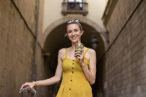 Портрет улыбающейся женщины в летнем платье, стоящей с напитком — стоковое фото