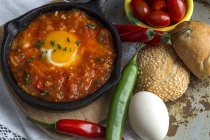 Fried egg with tomato and red and green peppers in frying pan — Stock Photo