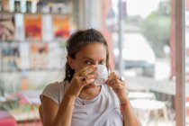 Bella donna seduta in mensa e bere una tazza di caffè. — Foto stock