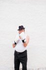 Adult man in hat and white boxing gloves at rough wall. — Stock Photo