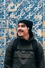 Fröhlicher Touristenmann steht an Wand mit blauen Fliesen — Stockfoto