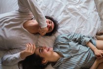 Fröhlicher junger Mann und Frau auf Bett liegend — Stockfoto