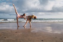 Amiche che fanno esercizi sulla spiaggia sotto il cielo nuvoloso — Foto stock