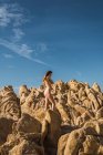 Vista lateral de mulher nua irreconhecível de pé e posando em rocha áspera. — Fotografia de Stock