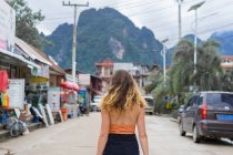 Back view of woman standing on asphalt road in the village. — Stock Photo