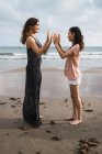 Lächelnde Mutter mit Tochter beim Kuchenspiel am sommerlichen Meeresufer — Stockfoto