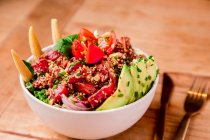Tigela de salada vegetal saborosa com abacate em mesa de madeira — Fotografia de Stock