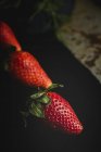 Close-up of textured delicious strawberries on black surface — Stock Photo