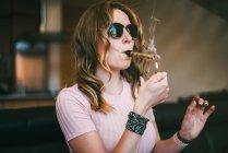 Mulher fumando maconha em um copo contundente — Fotografia de Stock