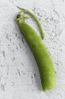 Close-up of green pea pod on white shabby surface — Stock Photo