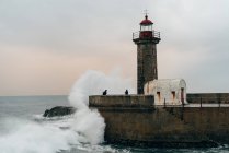 Torre faro sul molo dell'oceano ondulato, Oporto, Portogallo — Foto stock