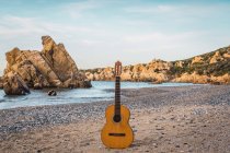 Classic acoustic guitar placed on sandy beach at the ocean. — Fotografia de Stock