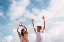 Rire adolescent garçon et fille debout avec les bras devant ciel — Photo de stock